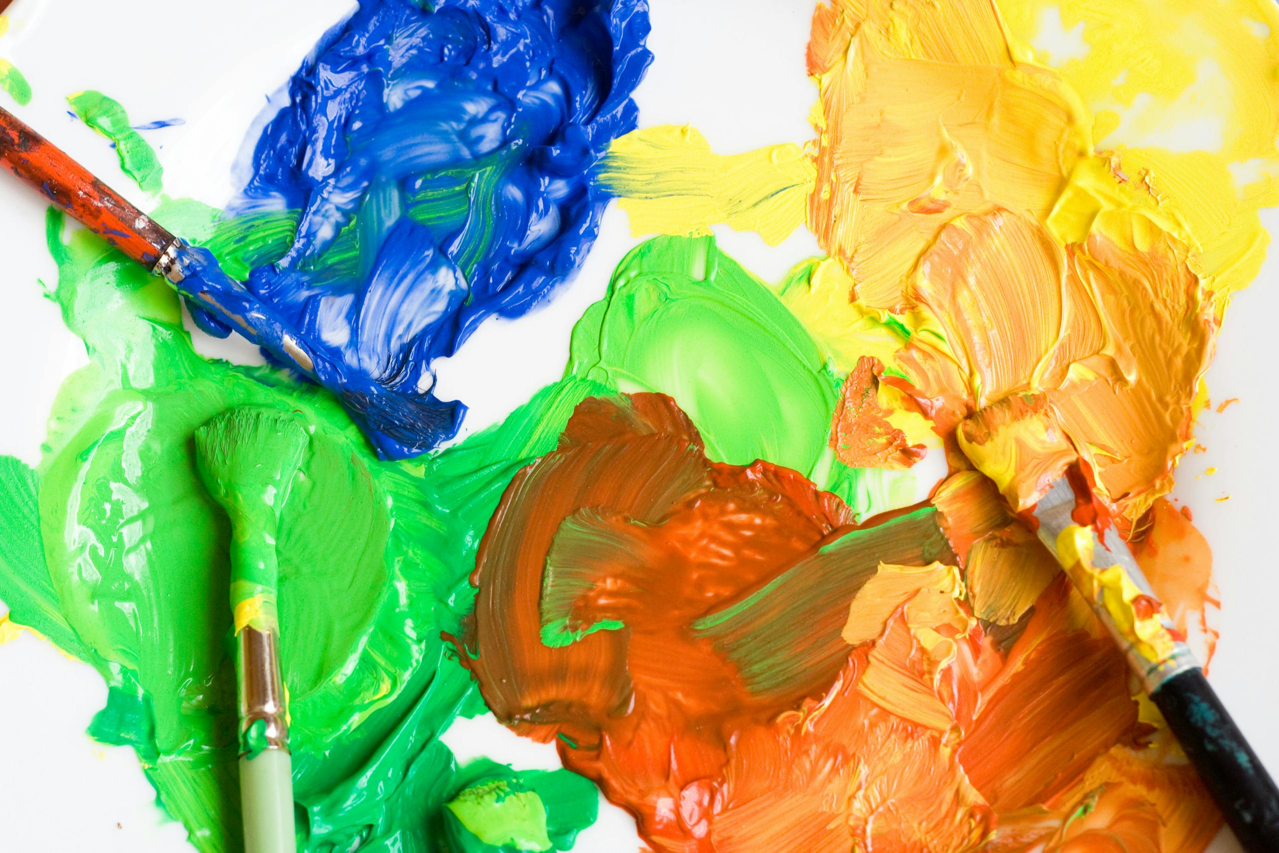 Close-up of a colorful paint palette with brushes showing creativity and art expression.